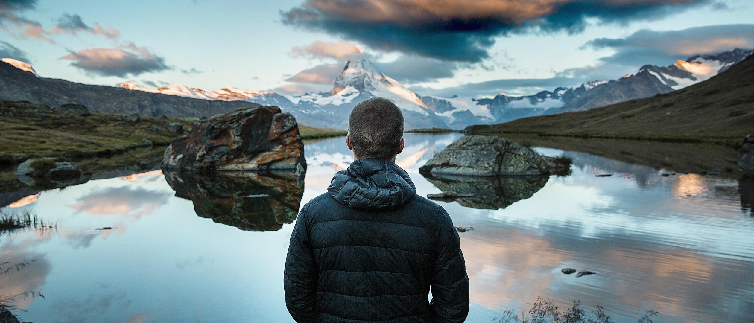 Man overlooking a mountain lake.